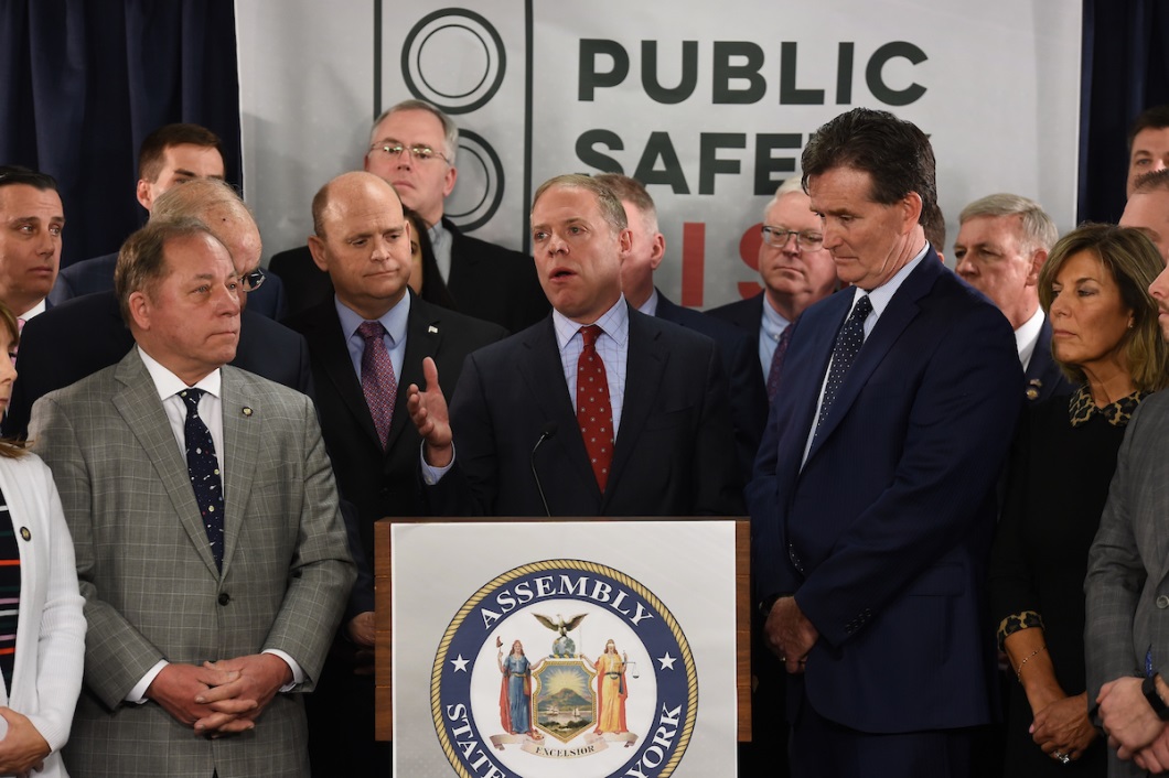 Assemblyman Steve Hawley (R,C,I-Batavia) [left] listens as Assembly Minority Leader Will Barclay (R,C,I,Ref-Pulaski) [at podium] speaks on the dangers of the ‘Green Light Law’